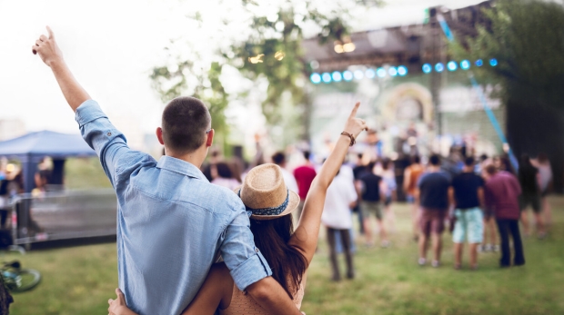 Young Caucasian couple toasting on a music festival.