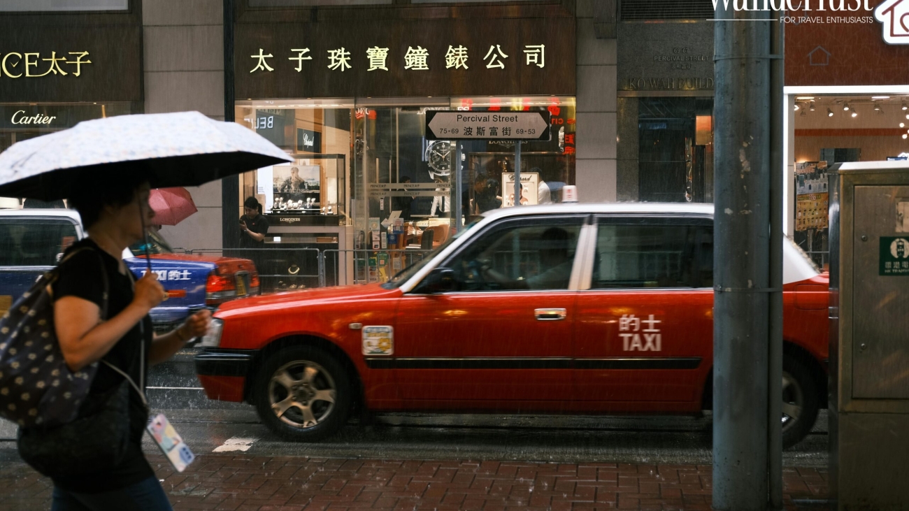 A tourist with an umbrella walks on a wet cobblestone street during a rainy day in China.
