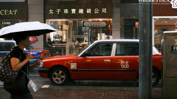 A tourist with an umbrella walks on a wet cobblestone street during a rainy day in China.
